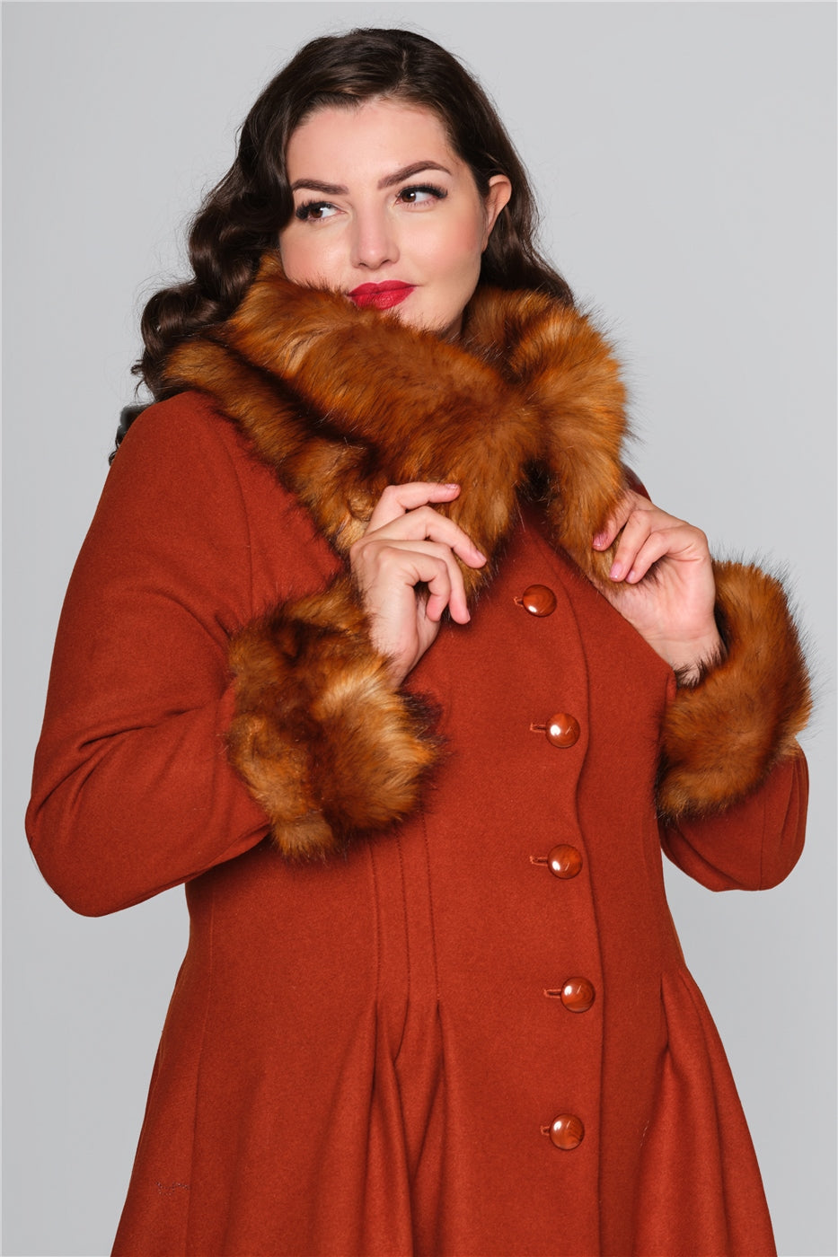 Brunette woman wearing a vintage rust colour swing coat with thick fur collar and cuffs