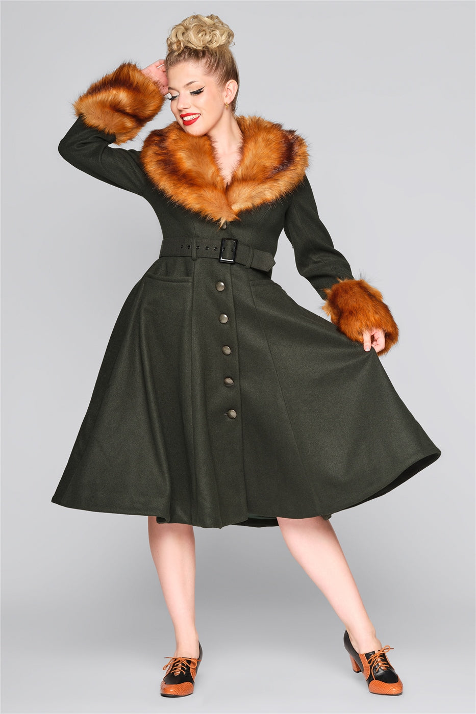 Elegant woman dressed in a vintage dark green swing coat with a fur trim