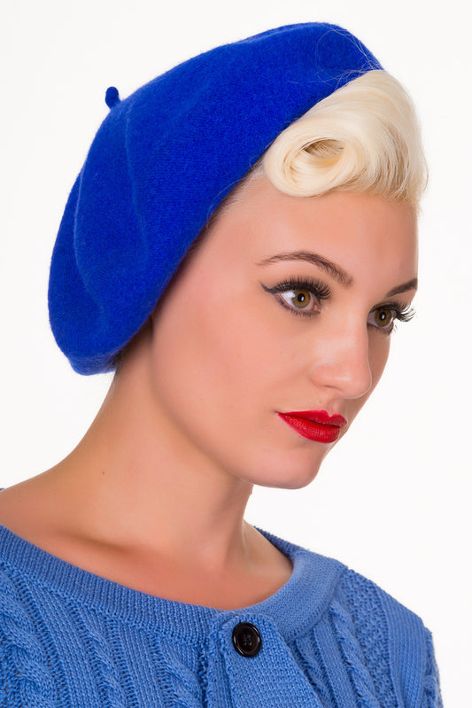 Blonde woman with victory rolls in her hair wearing bright red lipstick and a blue beret hat 