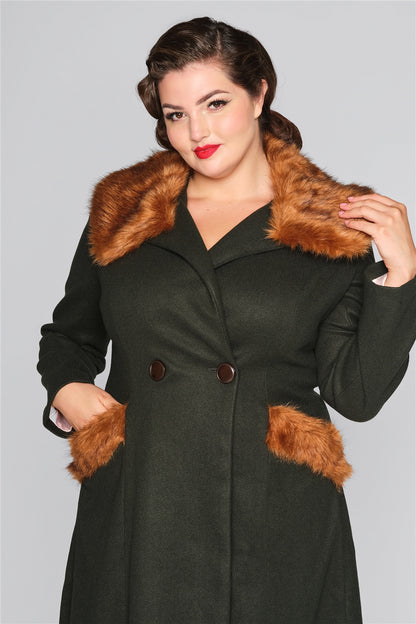 Brunette woman wearing bright red lipstick and a vintage dark green coat with a brown fur trim collar and pockets