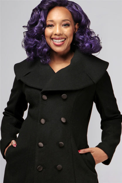 close up of smiling pinup style model wearing a black vintage coat with a wide collar and front buttons