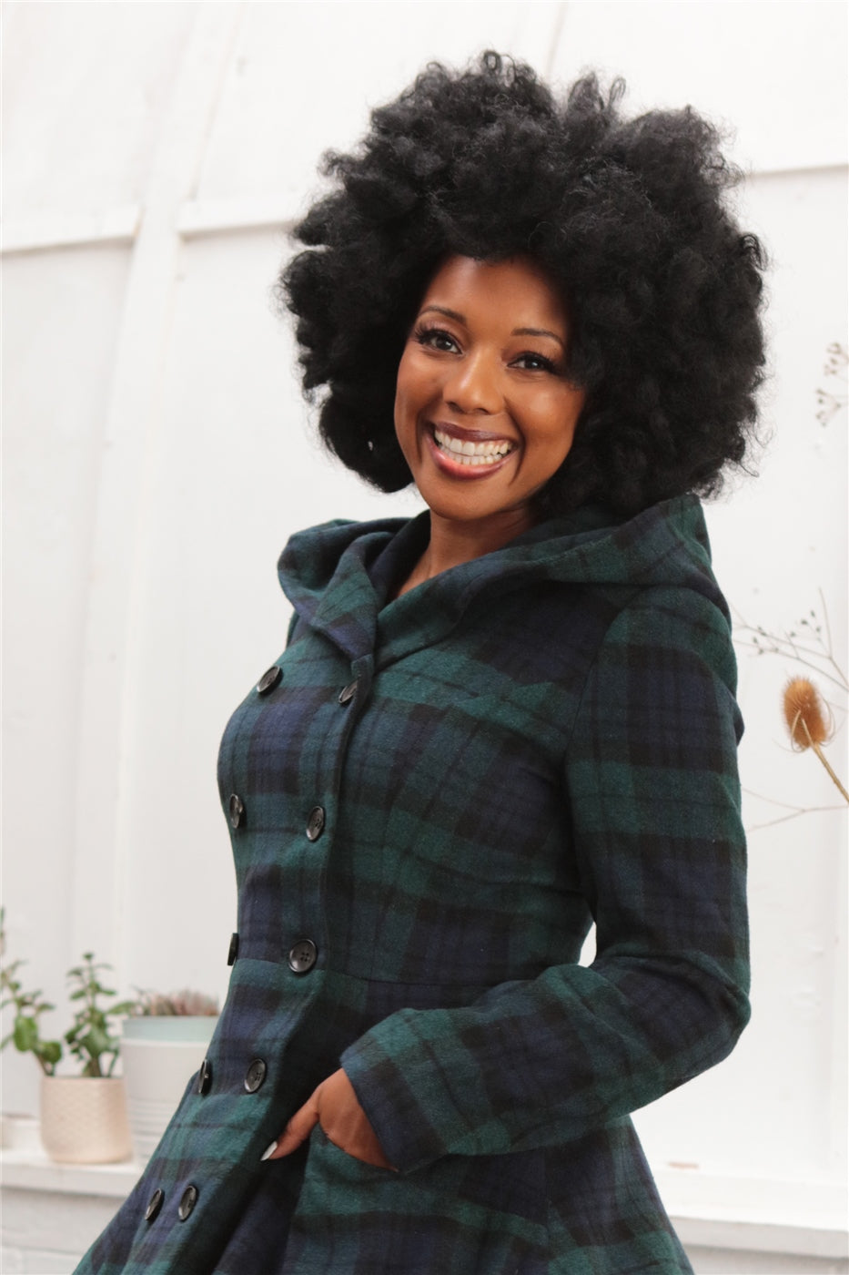 Smiling vintage pinup model wearing a vintage navy and green tartan winter coat