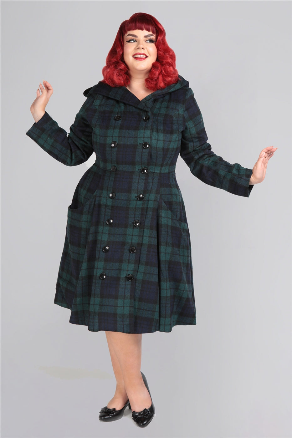 Red haired plus size model with 50s makeup posing in a knee length coat