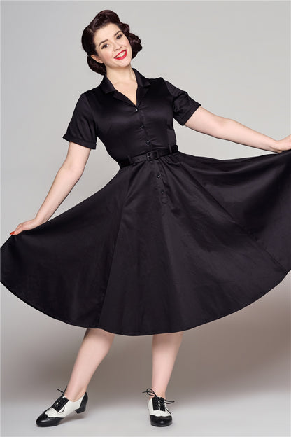 Elegant woman with radiant smile holding out the skirt of her black dress