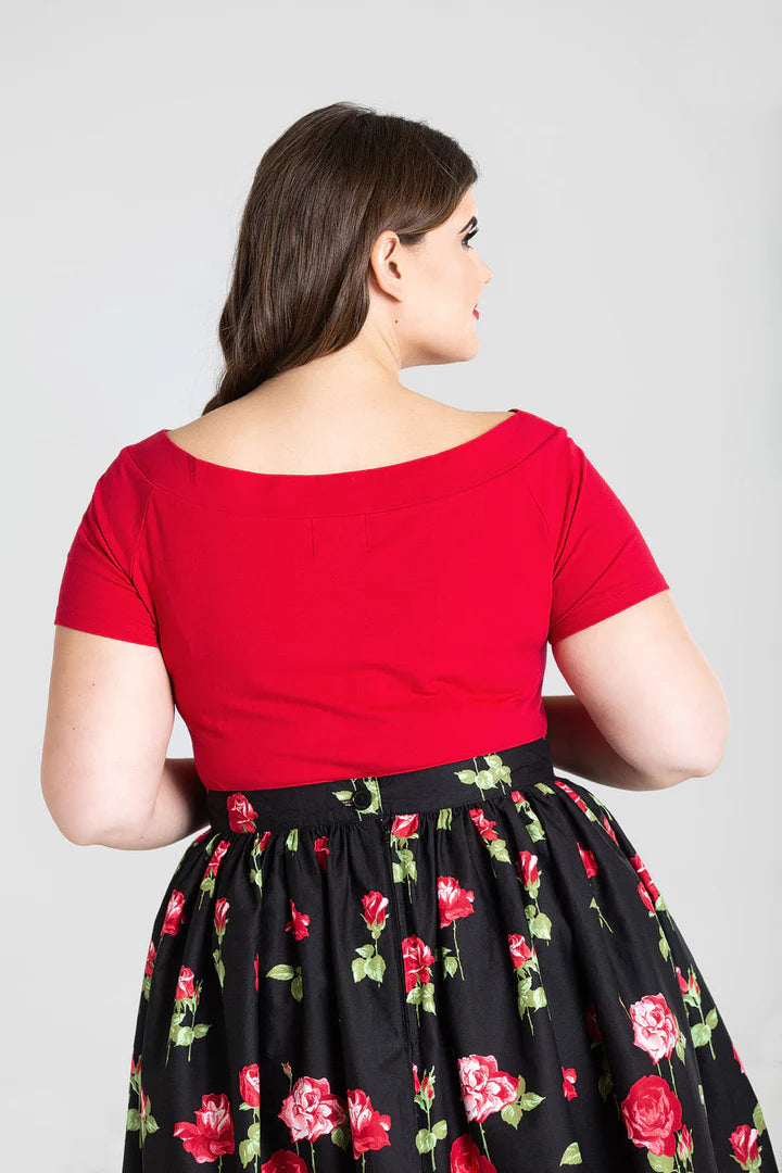 A curvy brunette model facing away from the camera wearing the Red Alex Top and Rose print skirt by Hell Bunny