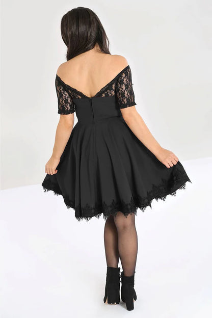 Young brunette woman wearing a black mini dress with a deep V cut lace back and flared skirt with a lace trim.