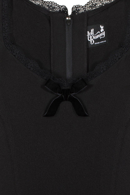 Close detail photo of the lace neckline and velvet bow at the front of the black dress 
