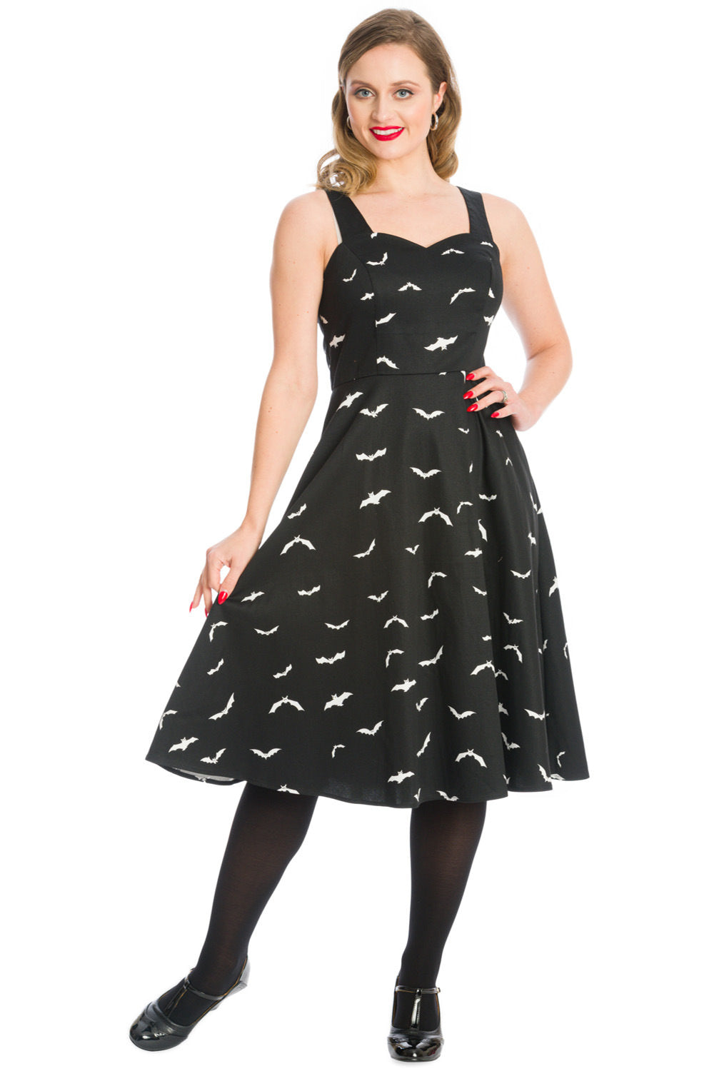 Blonde woman with a joyful smile standing confidently in a stylish black swing dress featuring a whimsical white bat print.