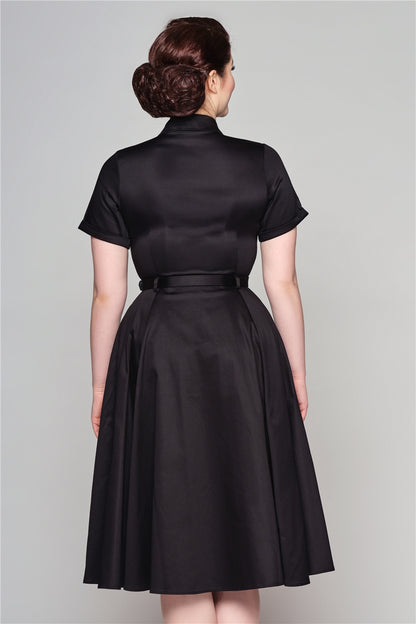 Elegant lady with a vintage aesthetic facing away from the camera showing the back of her 50s belted Caterina swing dress