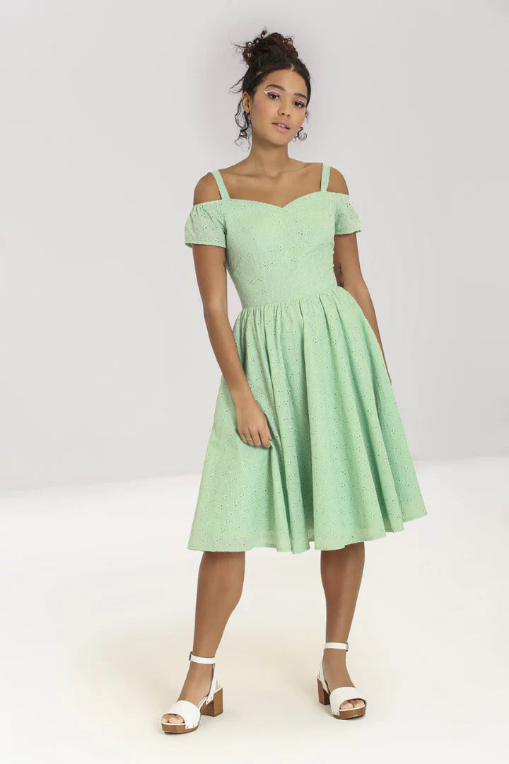 Pretty curly haired woman wearing pink eyeliner, white heeled sandals and a mint green cold shoulder 50s style dress