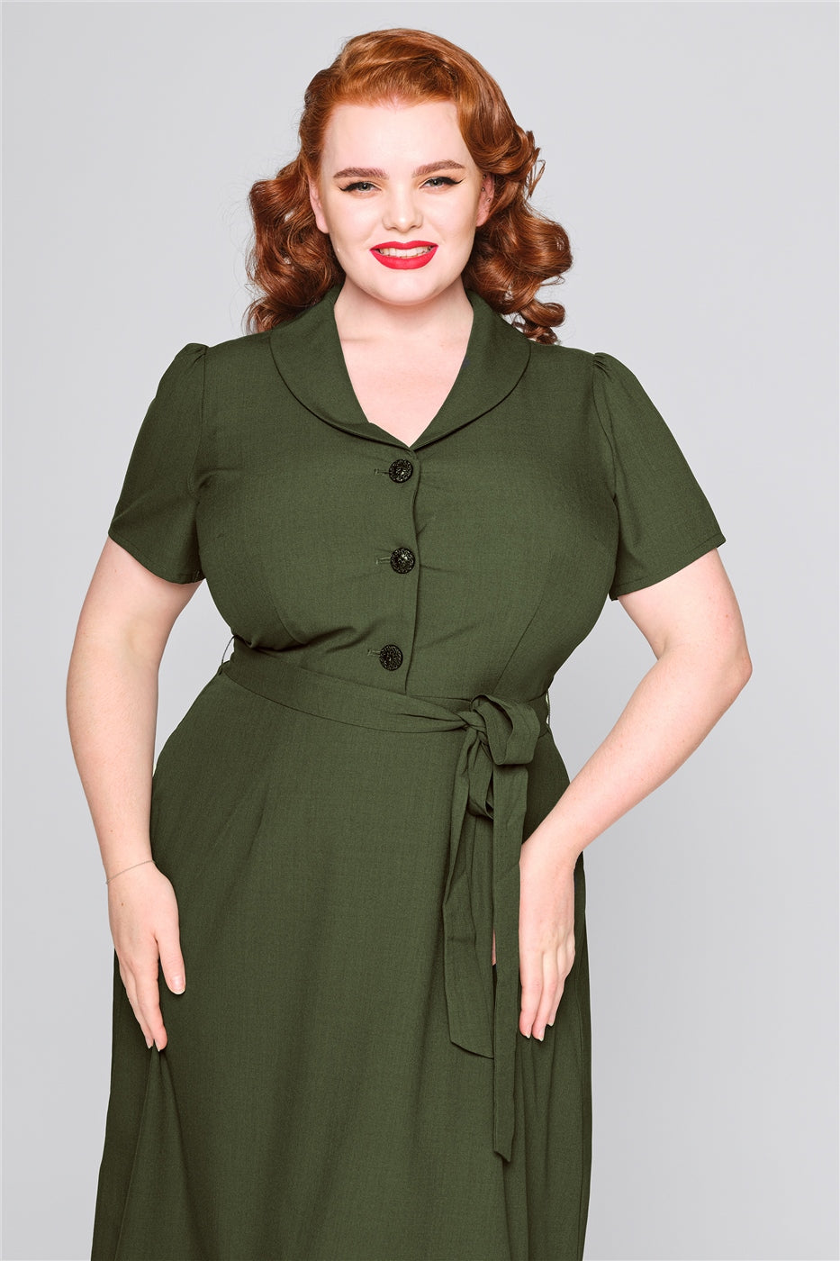 Red haired woman with a radiant smile wearing a green shirt style dress