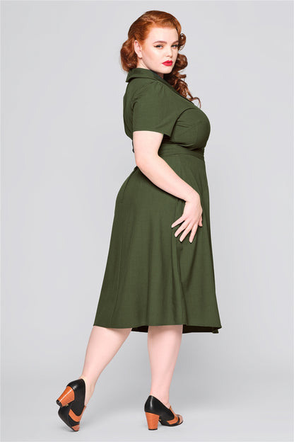 Sultry woman wearing red lipstick standing with one hip dropped wearing the green Hattie 40s dress