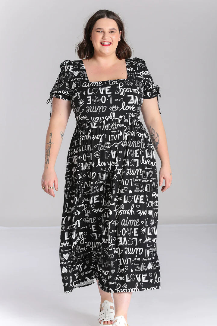 Curvy brunette woman with a radiant, happy smile wearing red lipstickand the Love Yourself Maxi Dress which features a square neckline and a white writing print