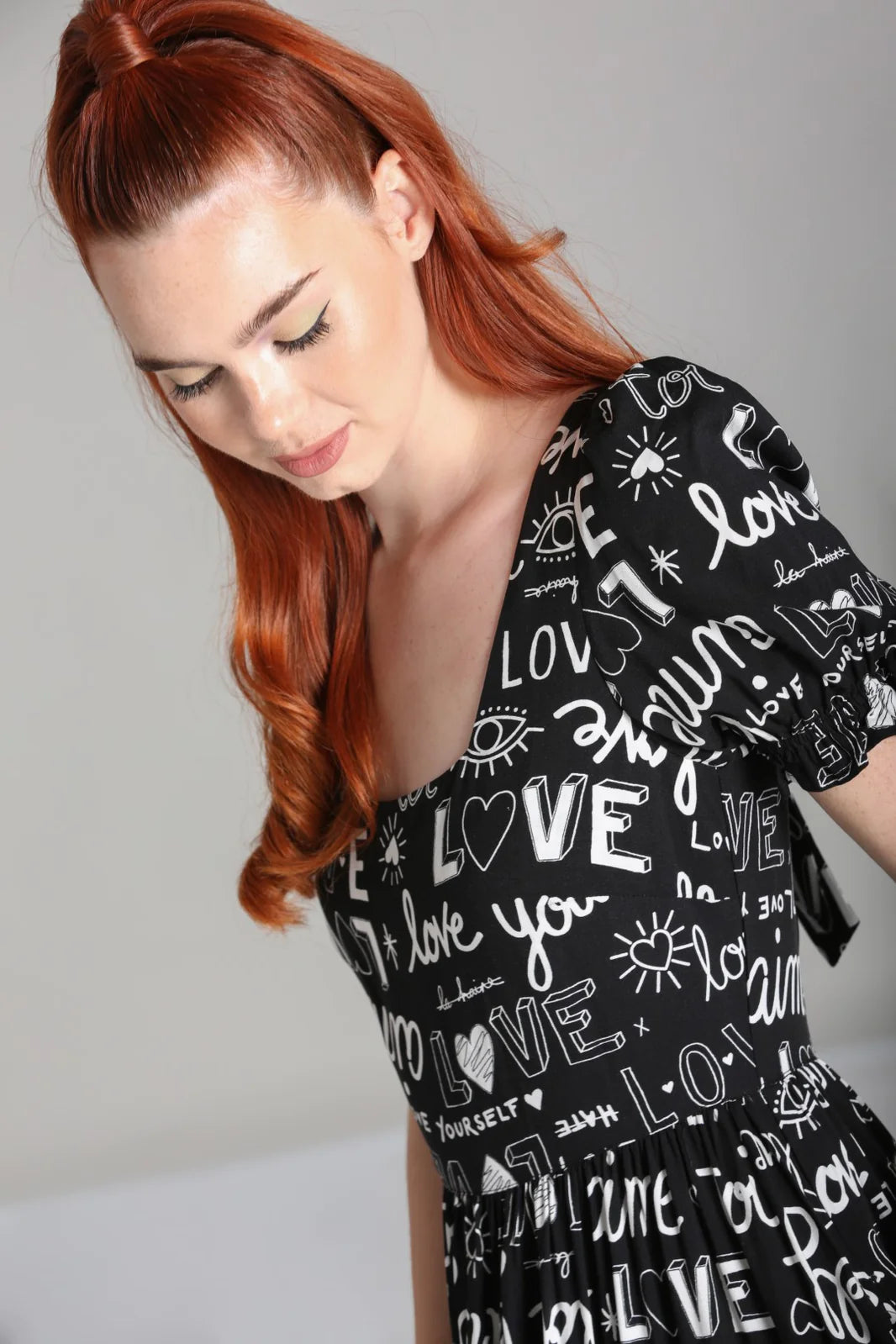 Close up of a young woman with long red hair wearing the Love Yourself black maxi dress by Hell Bunny
