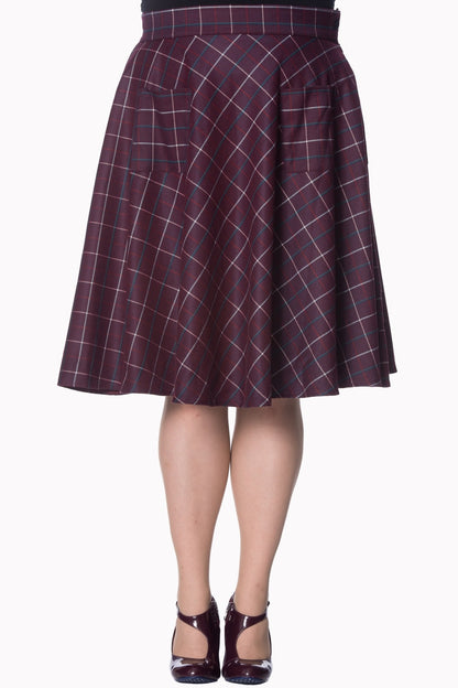 Plus model wearing a knee length deep plum checked swing skirt  and plum coloured shiny shoes