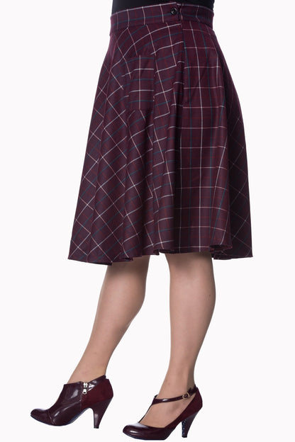 Side profile of a model wearing a plum coloured 50s style checked swing skirt and deep plum coloured heeled ankle boots