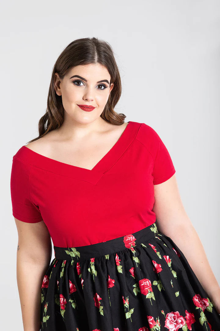 Brunette model with brown eyes wearing the red Alex Top by Hell Bunny and a black skirt with a red rose print 