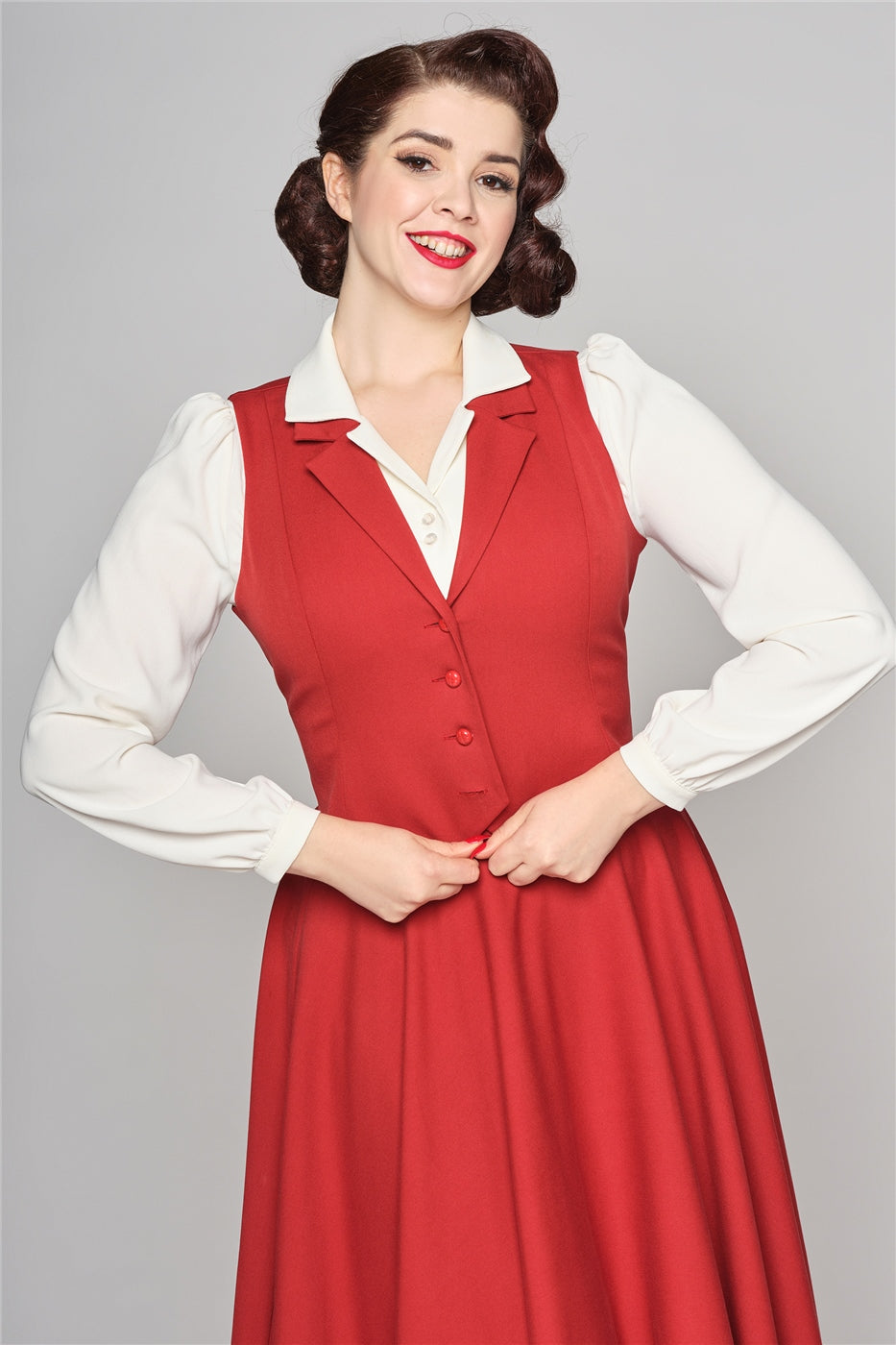 Retro style woman wearing her hair in a 50s style up-do with a long sleeved cream blouse and a red swing skirt