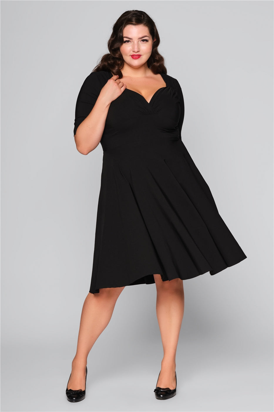 Brunette curvy model swishing her mid length black dress