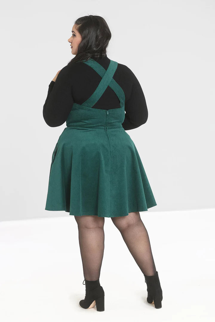 Wonder Years Green Pinafore Dress from the back on a plus size model who also wears a high neck black top, sheer black tights and chunky black boots