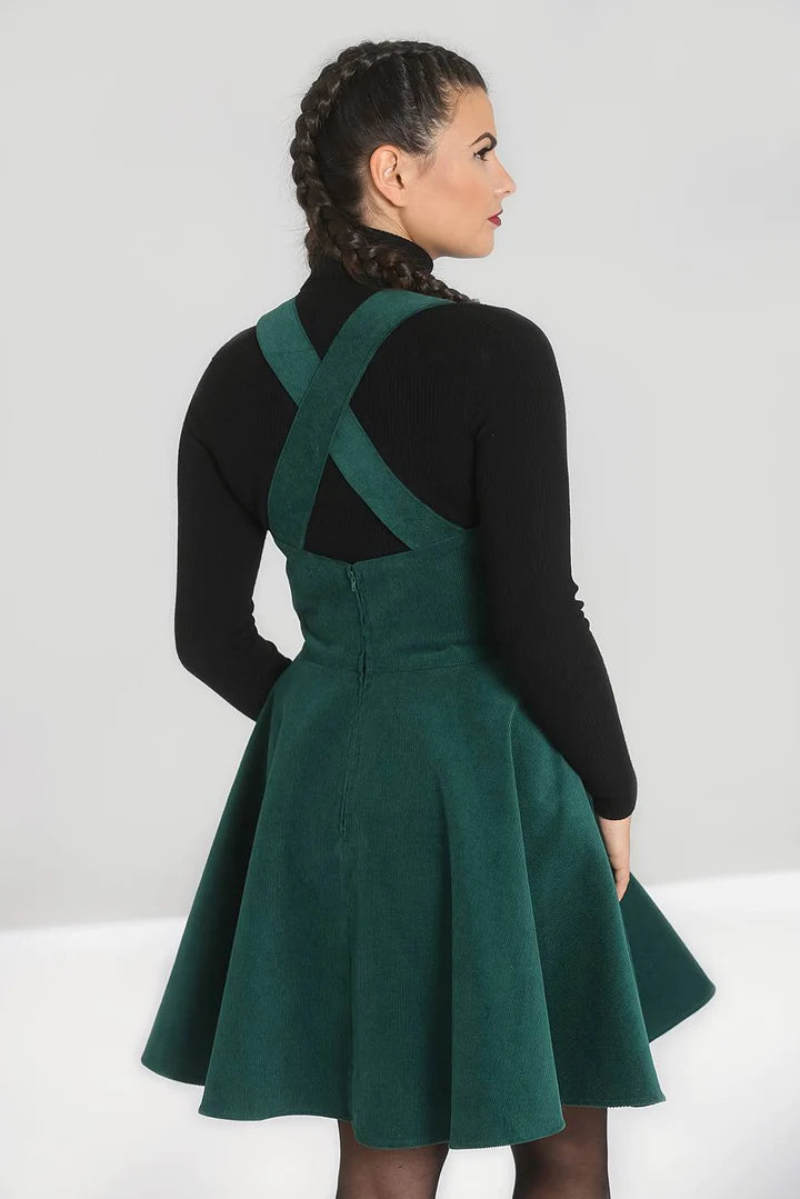 Woman with her hair in a plait showing the cross-straps at the back of her green pinafore dress