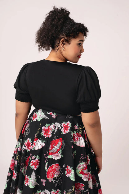 Woman wearing a black dress with floral patterns on a white background