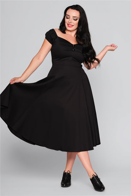 Dark haired vintage woman holding the skirt of her black dress