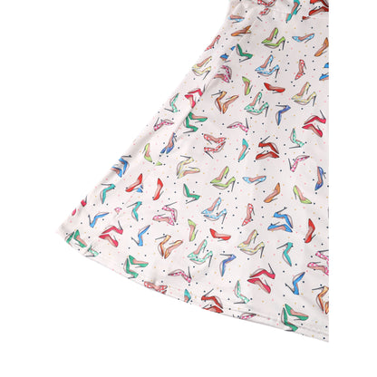 Close-up of the lower part of the Claudia Cream Stiletto Print Swing Dress by Dolly & Dotty, featuring a colorful pattern of stiletto heels in shades of green, pink, blue, and red on a cream background. The flared swing skirt showcases the playful, retro shoe design in vibrant detail.