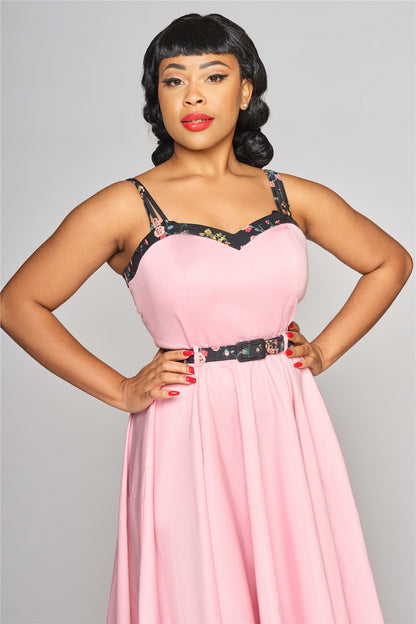 Dark haired woman standing with her hands on her hips wearing the pink Nova contrast belted swing dress by Collectif