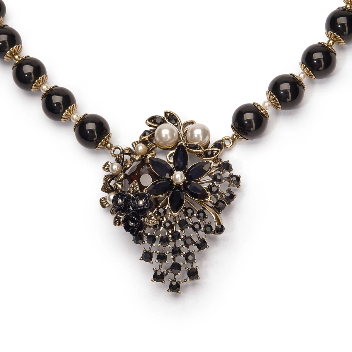 Necklace with black beads and decorative pendant on a white background