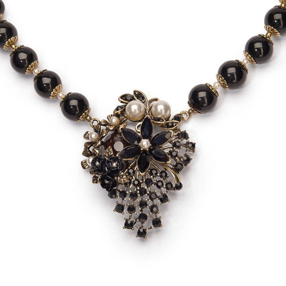Necklace with black beads and decorative pendant on a white background