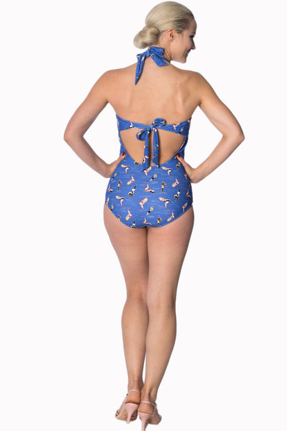 Pin Up style blonde model standing with her hands on her hips wearing a halter neck tie back swimsuit 