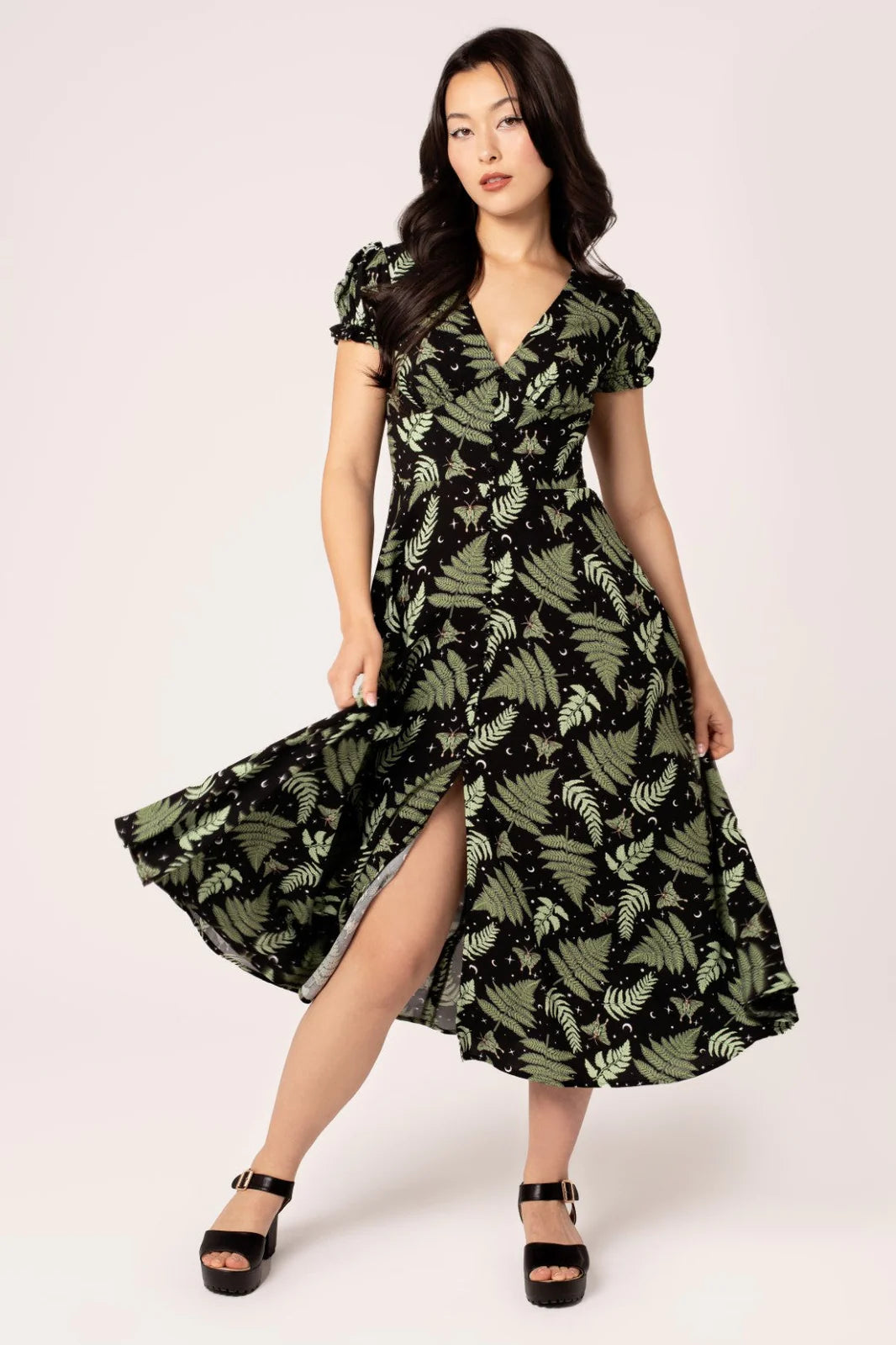 Woman wearing a green leaf-patterned dress on a white background