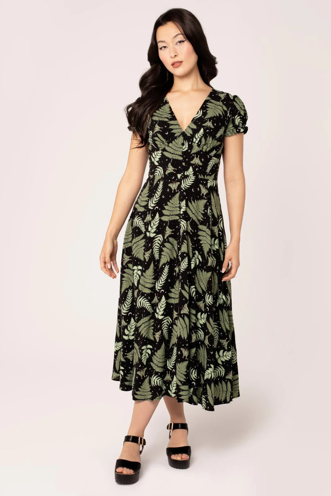 Woman wearing a green leaf-patterned dress on a white background
