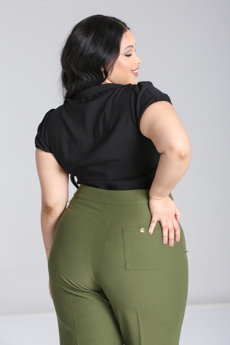 Happy plus size model facing away smiling over her shoulder wearing natural makeup and high waisted trousers with an embroidered blouse