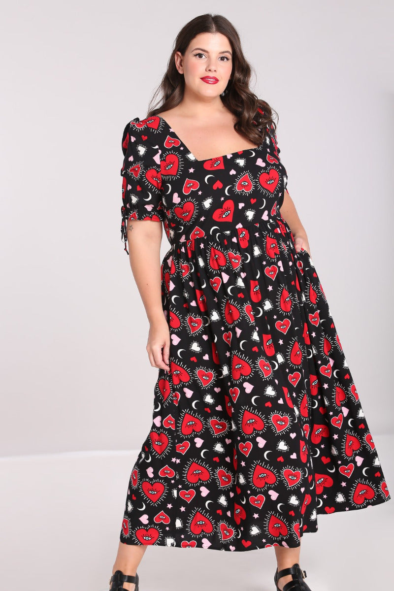Elegant curvy brunette woman with red lisptick and subtle eyeliner wearing the Kate Heart Maxi Dress and black flat sandals