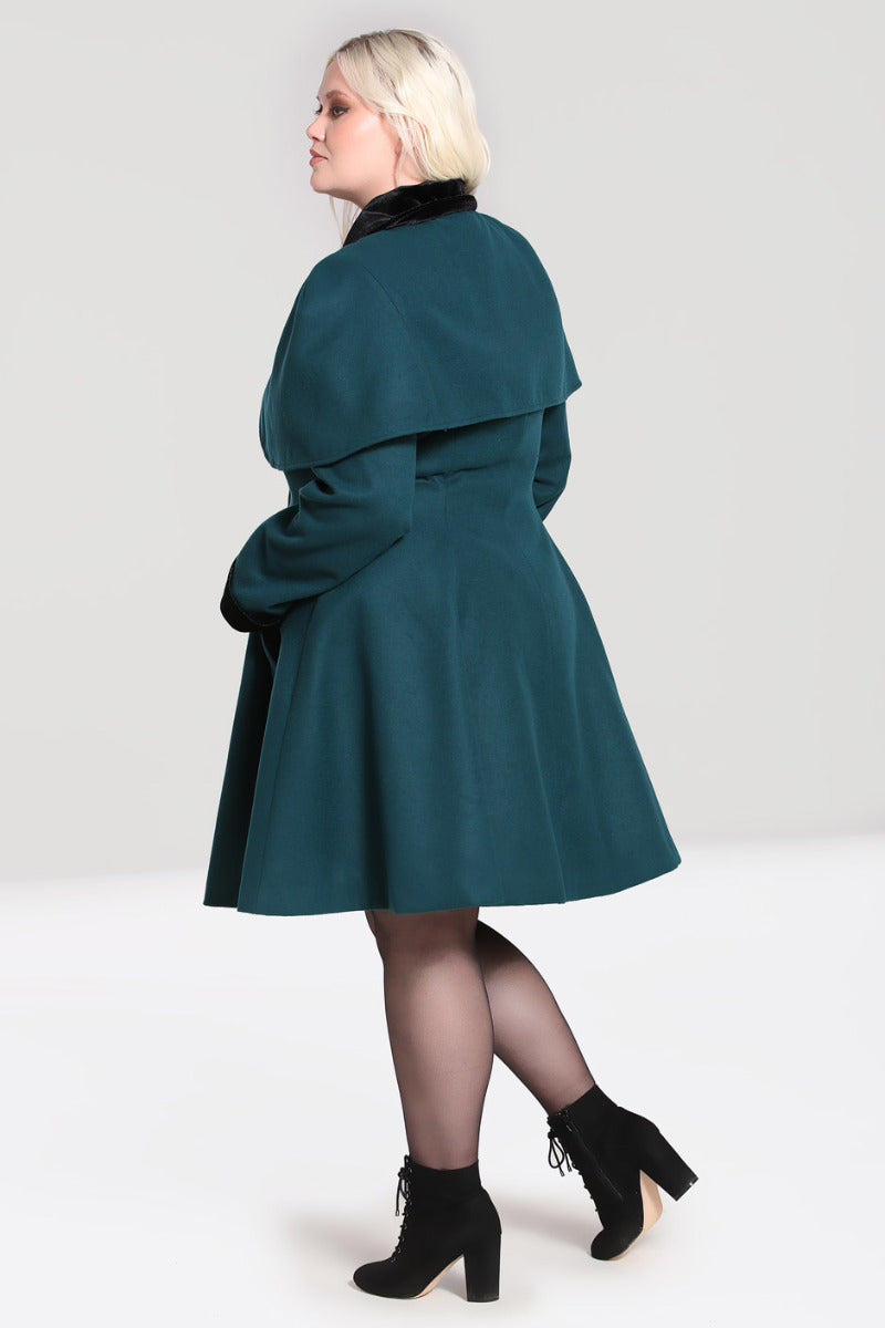 Glamorous curvy model wearing chunky black ankle boots and a vintage style dark green swing coat with matching cape