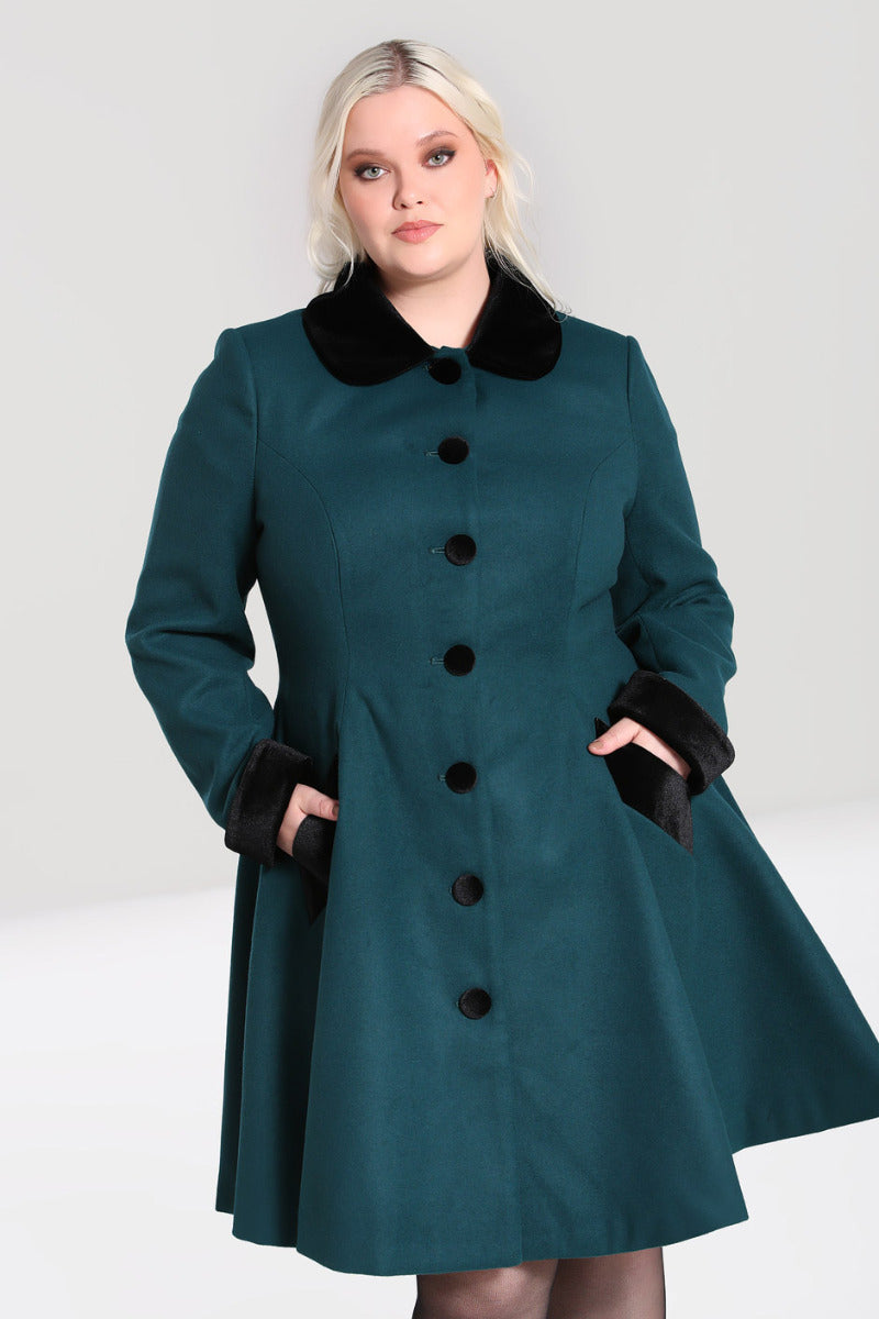 Pretty blonde curvy model wearing a luxurious winter coat in dark green with black collar, cuffs and buttons at the front