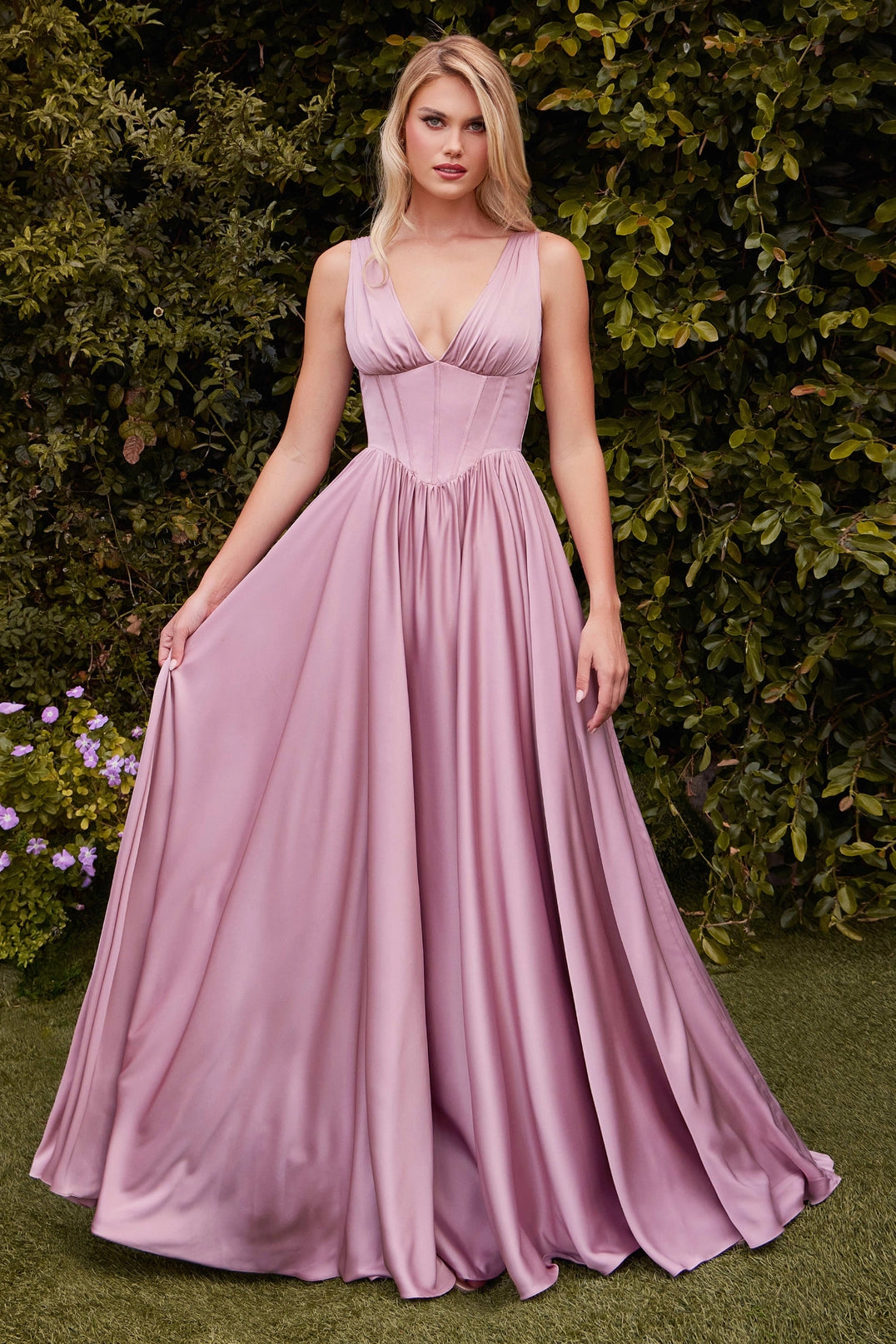 Woman wearing a pink gown standing against a green bush