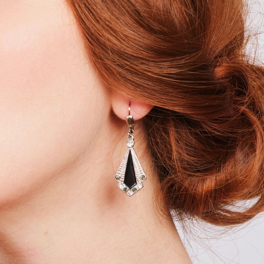 Close-up of 1920s-inspired Art Deco earring by Lovett & Co, shown worn on ear, featuring a fan-shaped design with black enamel, silver-tone metal, and crystal accents