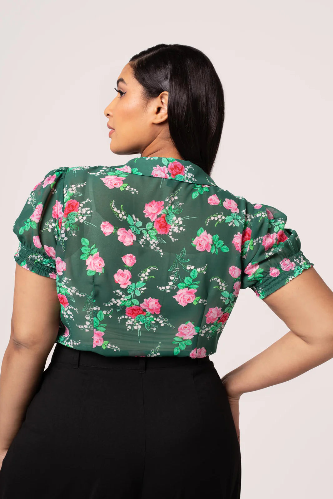 Woman wearing a green floral blouse against a plain background