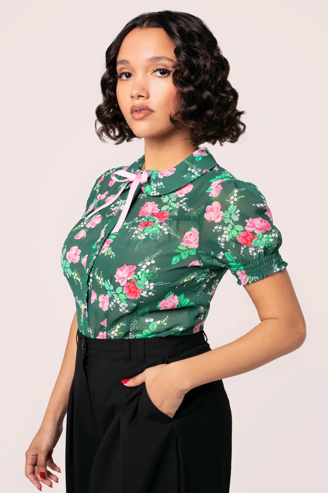 Woman wearing a green floral blouse with a white background