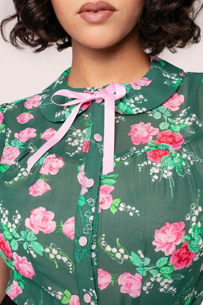 Green floral blouse with pink flowers and a pink ribbon on a white background
