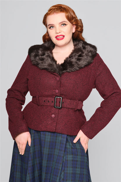 Curvy plus size model wearing bright red lipstick, a navy tartan skirt and a burgundy vintage style jacket with faux fur trim collar