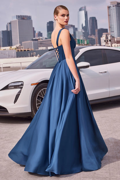 Woman in a blue evening gown standing in front of a white car with a city skyline in the background