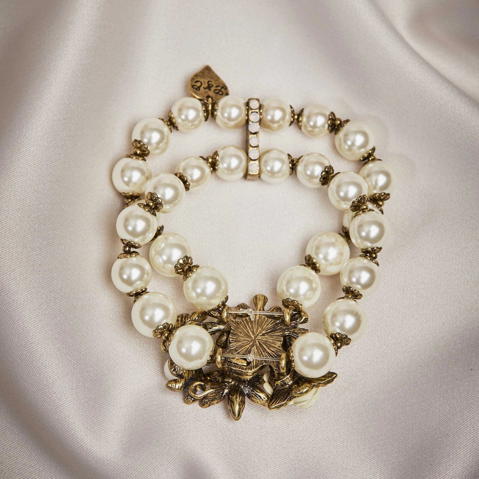 Pearl bracelet with gold clasp on a light fabric background