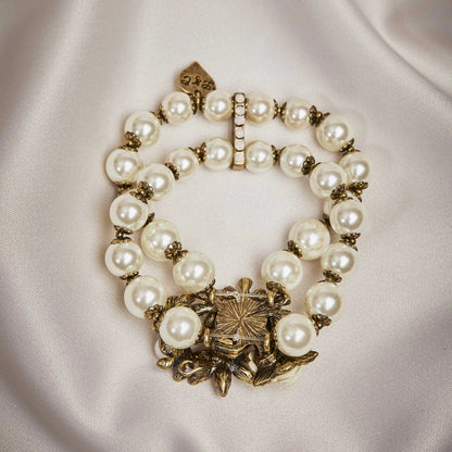 Pearl bracelet with gold clasp on a light fabric background