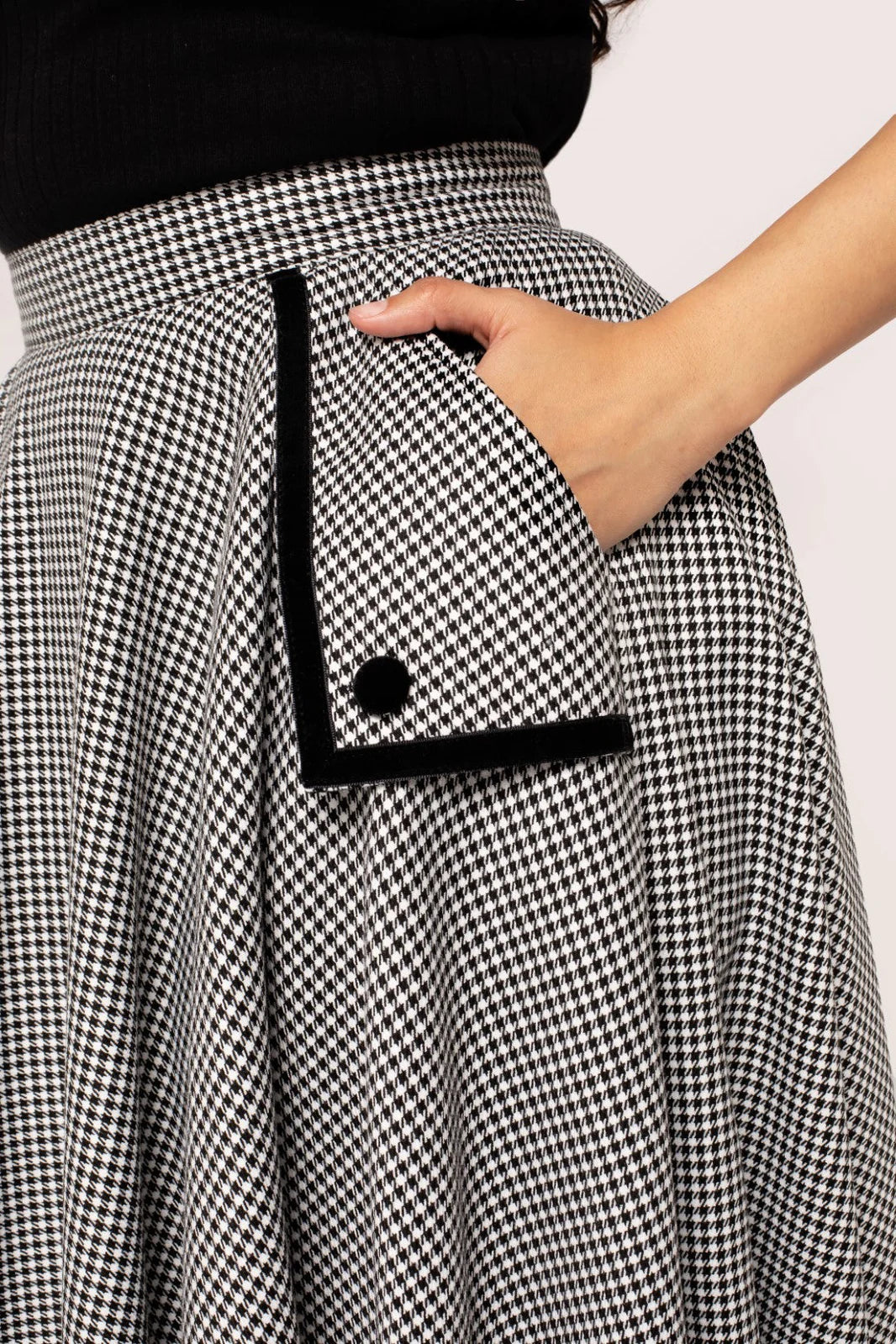Close up of a woman's hand in the pocket of the Hell Bunny Teddy 50s Skirt, showing the black button and black outline detail on the pocket.