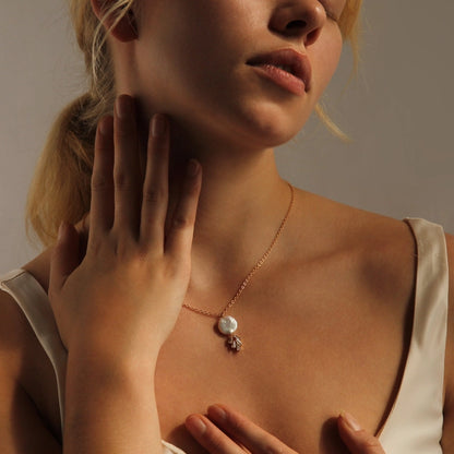 Young woman holding one hand up to her face. She is wearing an art deco style freshwater pearl necklace.