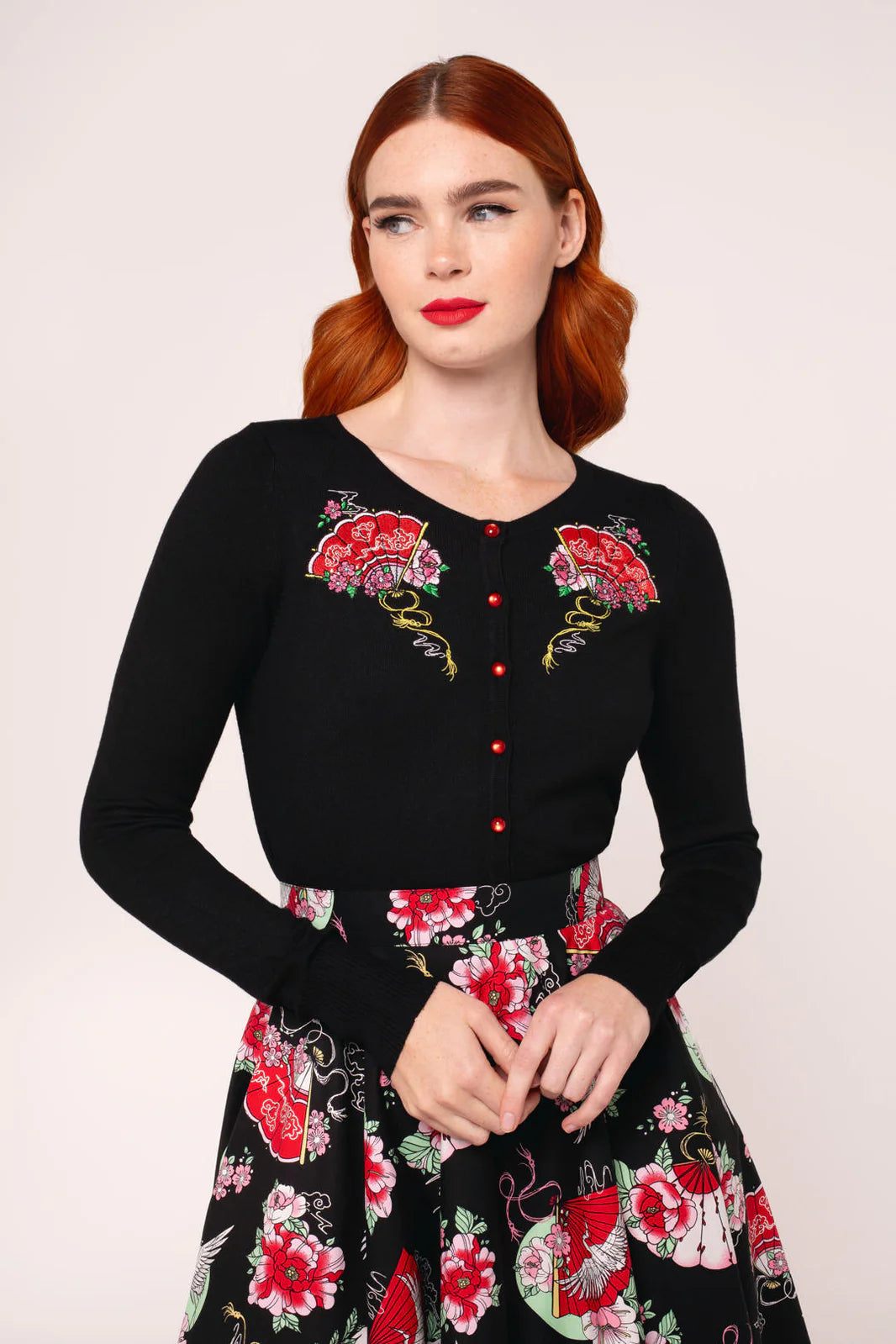 Woman wearing a black dress with floral embroidery on a white background